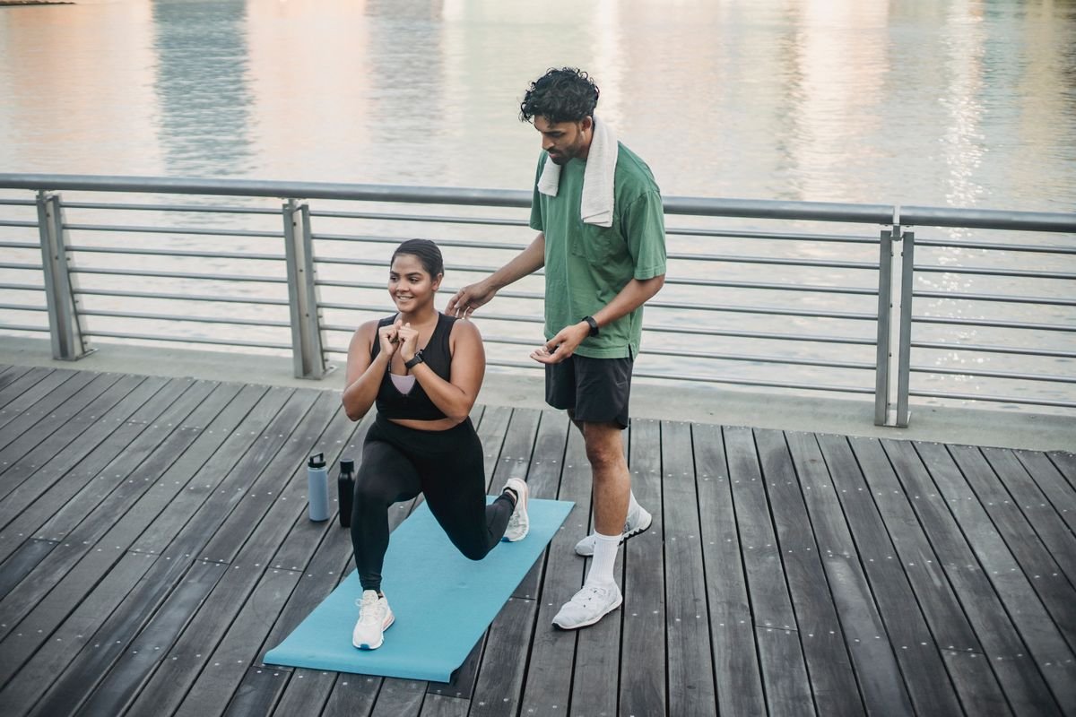 Teacher guiding a beginner into a simple yoga posture