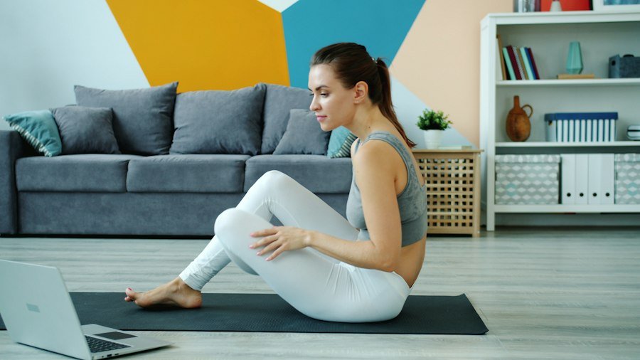 Student practising yoga at home in front of a laptop